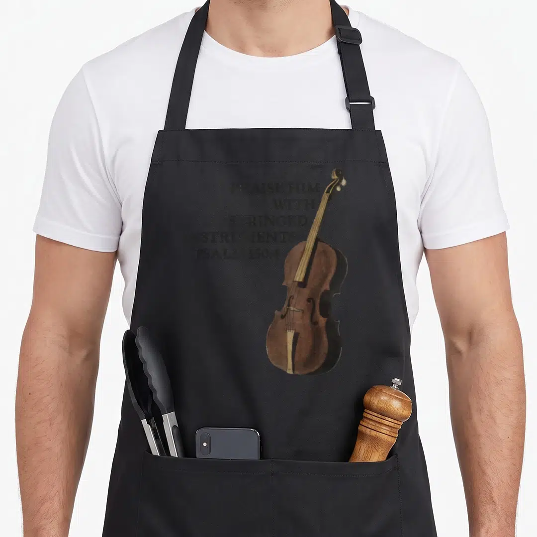 Double christian apron - Brown violin illustration next to black stacked text reading Praise Him With Stringed — shown on a black cotton canvas apron against a white background