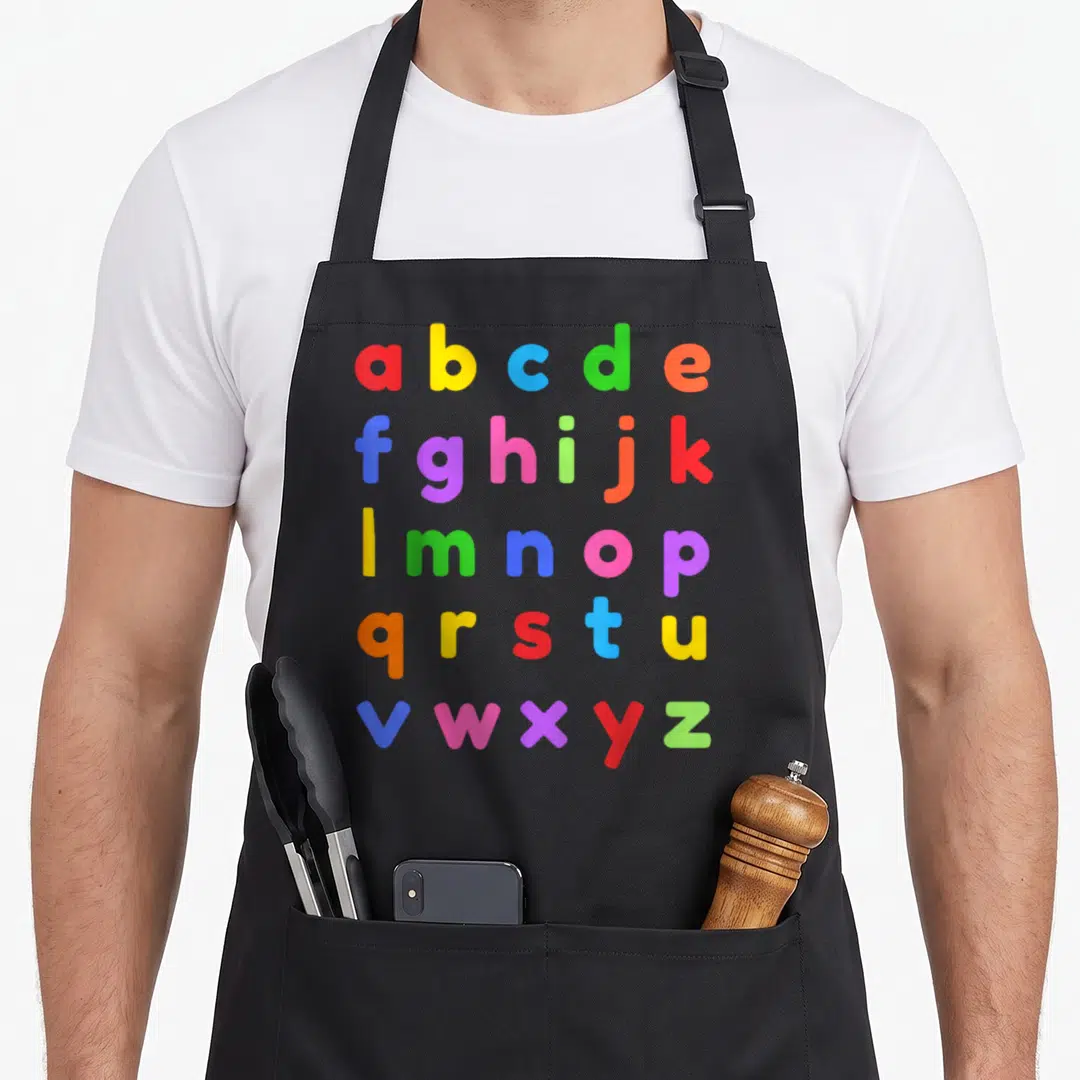 Lowercase teacher apron - colorful lowercase a-z alphabet letters in red yellow blue green orange purple pink on gray — shown on a black cotton canvas apron against a white background