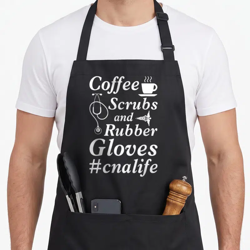 Coffee white nurse apron - Vertical white text reading Coffee Scrubs and Rubber Gloves with stethoscope and cup icons — shown on a black cotton canvas apron against a white background
