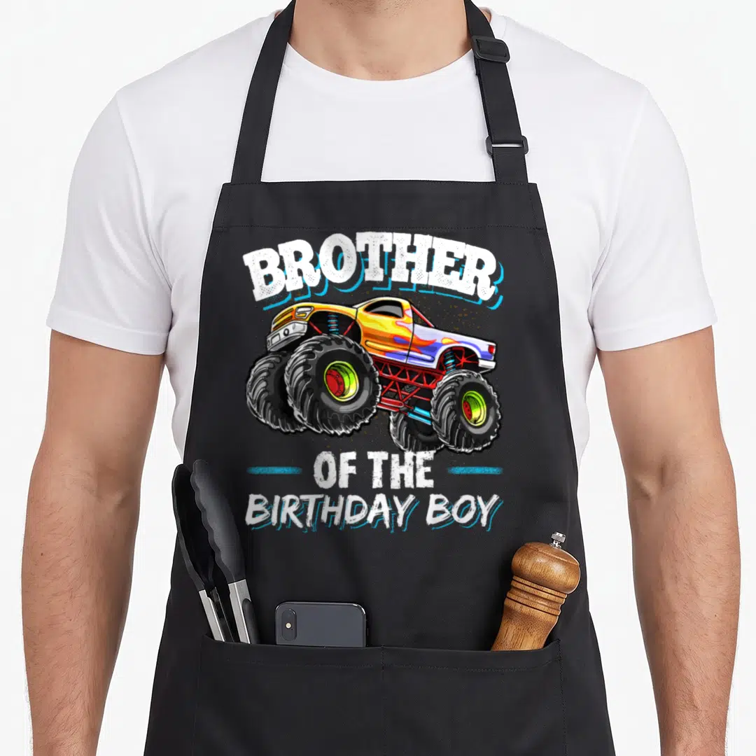 Brother birthday truck apron - Cartoon monster truck with Brother of the Birthday Boy text in white and blue — shown on a black cotton canvas apron against a white background