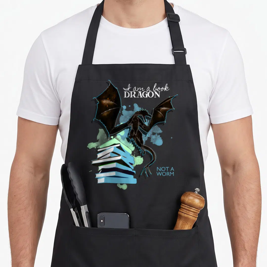 Worm dragon apron - Black dragon perched on stack of books with blue and green paint splashes — shown on a black cotton canvas apron against a white background