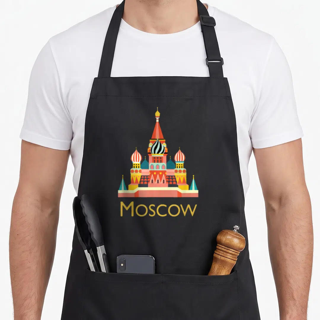 Moscow russia apron - Minimalist Saint Basil's Cathedral in red yellow blue green above Moscow text — shown on a black cotton canvas apron against a white background