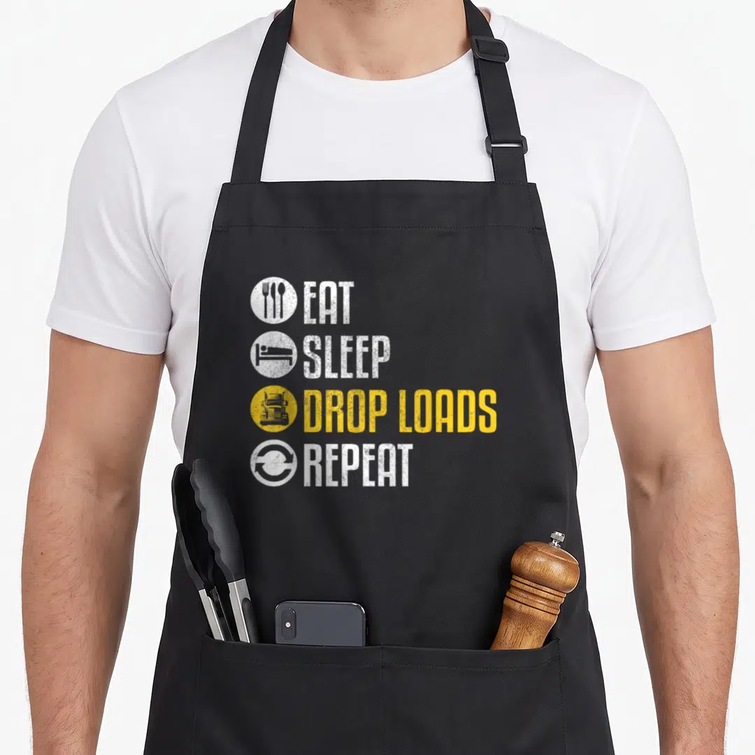Driver truck apron - Four stacked text lines with circular icons for eating, sleeping, trucking, and repeating in white — shown on a black cotton canvas apron against a white background