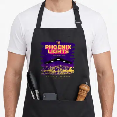 Phoenix alien ufo apron - Retro purple and yellow V-shaped UFO over Phoenix skyline with text I Know What I Saw — shown on a black cotton canvas apron against a white background