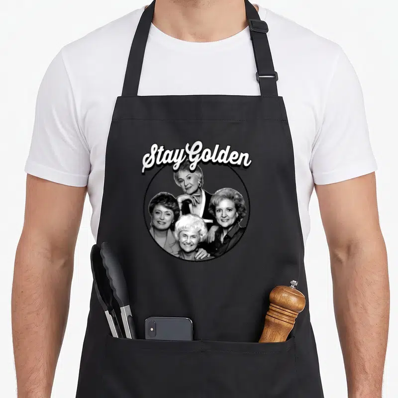 Funny stay golden apron - Four women in black circle under white Stay Golden text — shown on a black cotton canvas apron against a white background