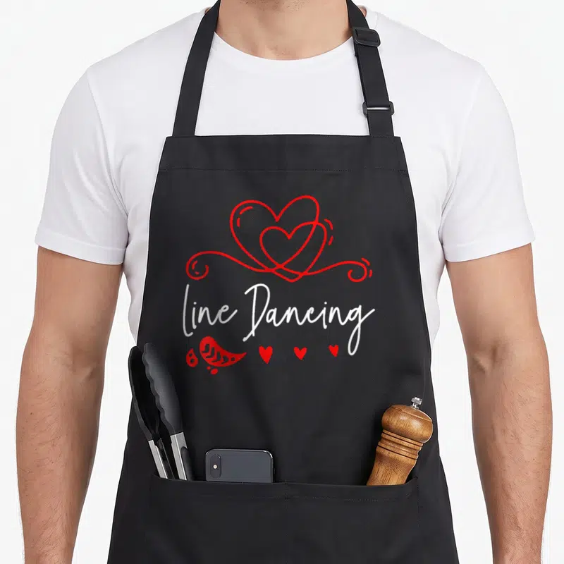 Vintage dancing line apron - Red interlocking hearts above white line Dancing script with paisley and small hearts below — shown on a black cotton canvas apron against a white background
