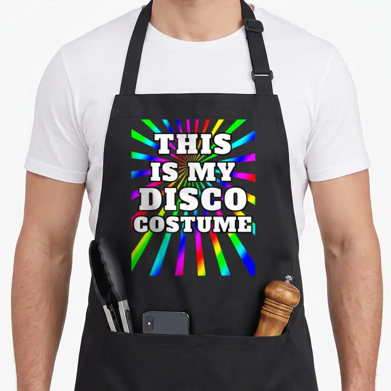 Disco costume 70s apron - White text reading THIS IS MY DISCO COSTUME over rainbow sunburst rays — shown on a black cotton canvas apron against a white background