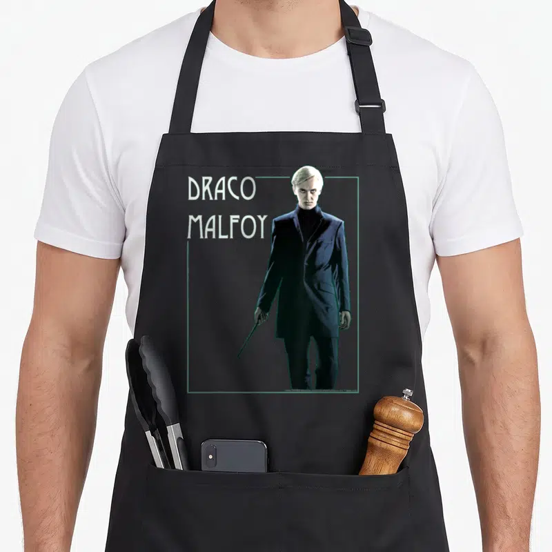 Draco simple apron - Draco Malfoy portrait in dark blue suit with white text and teal frame — shown on a black cotton canvas apron against a white background