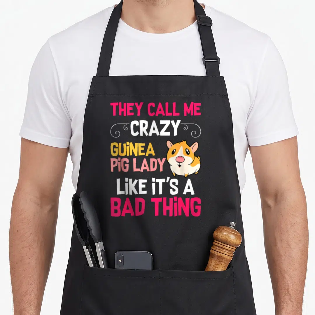 Call crazy guinea lady apron - Stacked colorful text THEY CALL ME CRAZY GUINEA PIG LADY with cartoon guinea pig — shown on a black cotton canvas apron against a white background