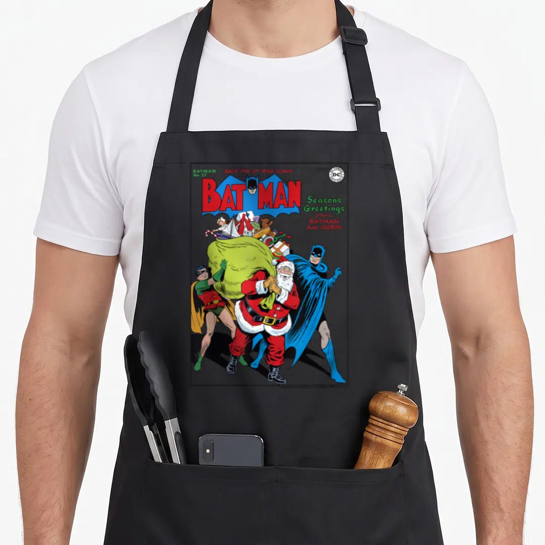 Season christmas robin apron - Batman Santa Robin comic cover with Back the 6th War Loan text in blue red green white — shown on a black cotton canvas apron against a white background