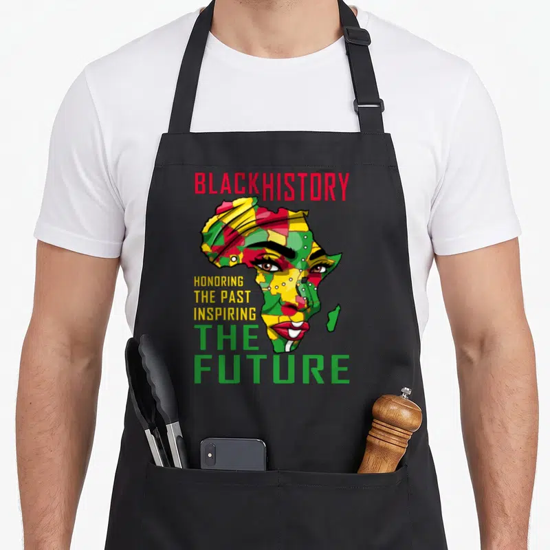 Past future it apron - Woman's face shaped like Africa map with red yellow green text — shown on a black cotton canvas apron against a white background