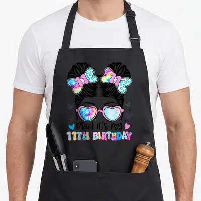 Bruh 11th birthday apron - Girl with space buns and tie-dye glasses wearing 11th birthday apron — shown on a black cotton canvas apron against a white background