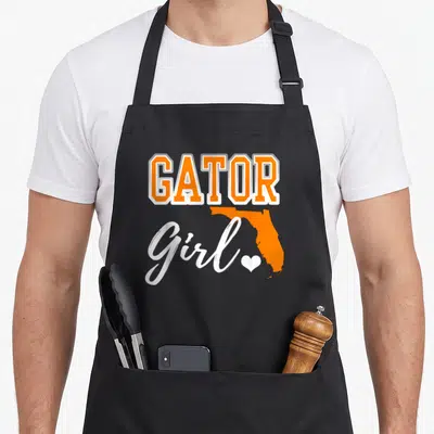 Map florida apron - GATOR Girl text with orange Florida map and white heart on black apron — shown on a black cotton canvas apron against a white background