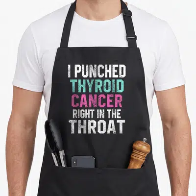 Punched thyroid apron - Stacked text I Punched Thyroid Cancer Right In The Throat in white teal and pink block letters — shown on a black cotton canvas apron against a white background