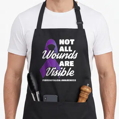 Wound fibromyalgia awareness apron - Purple awareness ribbon with white text NOT ALL Wounds ARE Visible FIBROMYALGIA — shown on a black cotton canvas apron against a white background