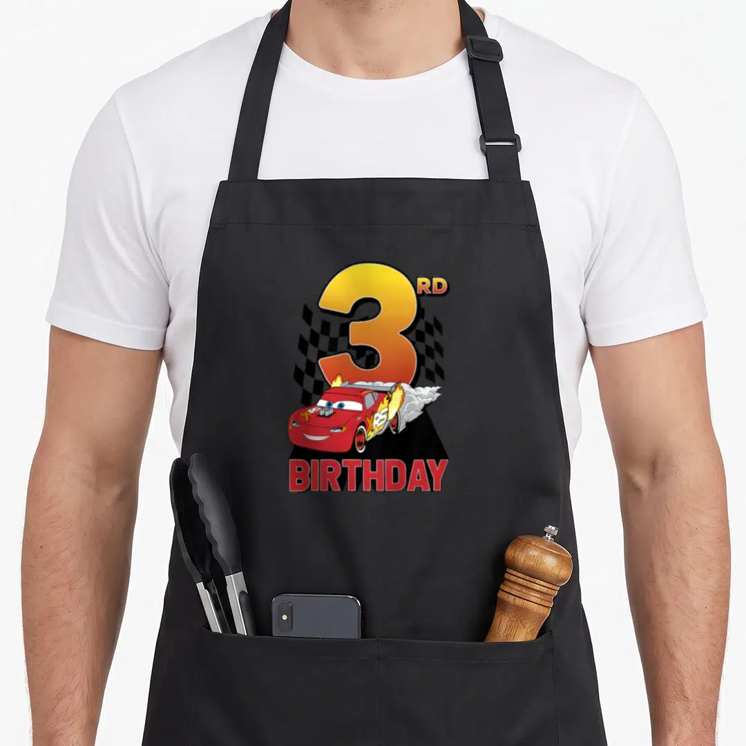 Youth 3rd car apron - Red race car with flames, large number 3, checkered flag, and BIRTHDAY text — shown on a black cotton canvas apron against a white background