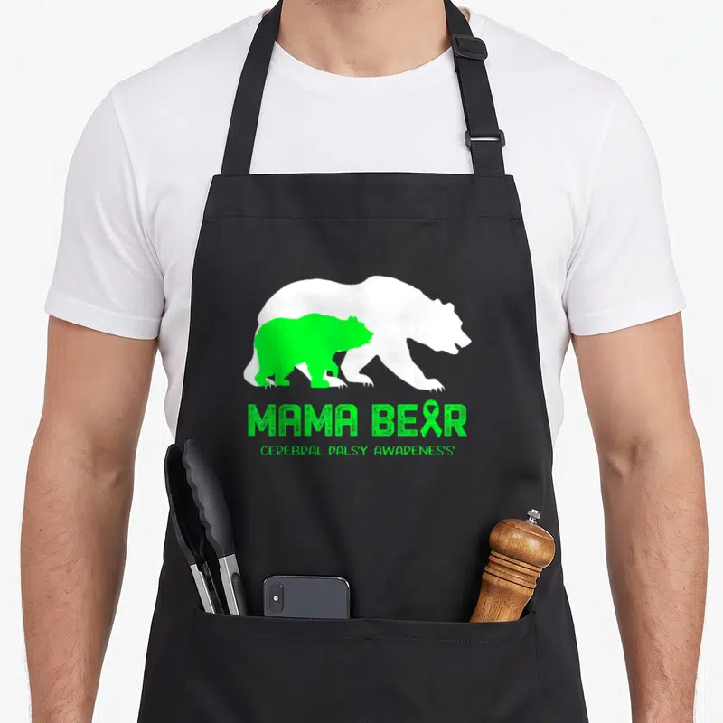 Cerebral mama bear apron - Green and white bear silhouettes with MAMA BEAR CEREBRAL PALSY AWARENESS text and ribbon — shown on a black cotton canvas apron against a white background