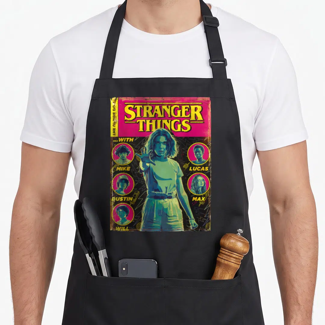 Shot stranger apron - Retro Stranger Things comic cover with girl and four named character portraits in magenta — shown on a black cotton canvas apron against a white background