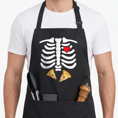 Junk halloween apron - White ribcage with red heart and two yellow pizza slices in cartoon style — shown on a black cotton canvas apron against a white background