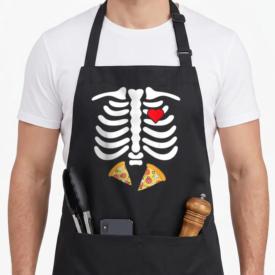 Junk halloween apron - White ribcage with red heart and two yellow pizza slices in cartoon style — shown on a black cotton canvas apron against a white background