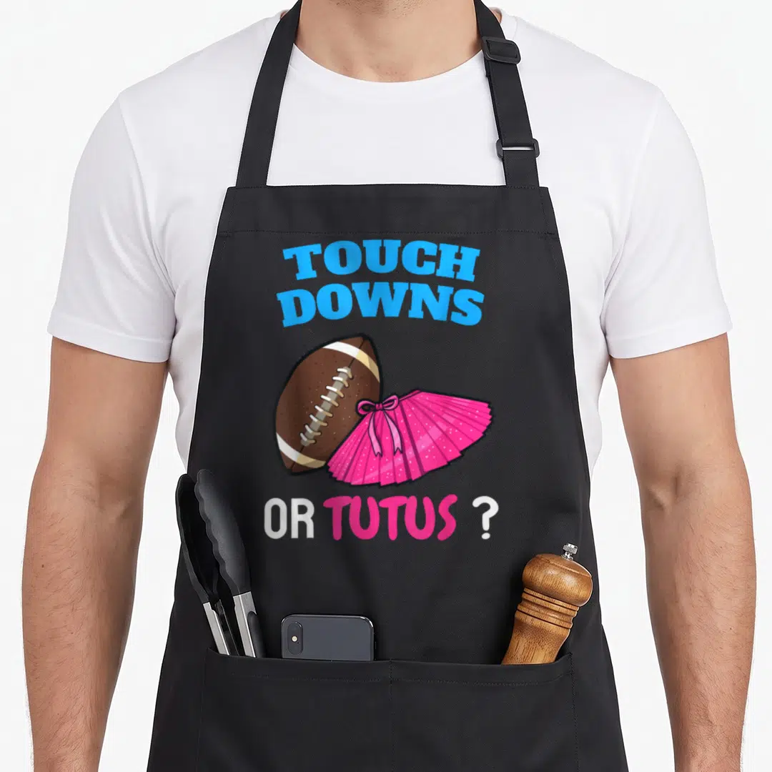 Tutus football apron - Cartoon football and pink tutu with arched blue Touchdowns text and Or Tutus question below — shown on a black cotton canvas apron against a white background
