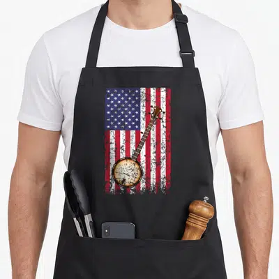 Banjo american flag apron - Distressed USA flag with brown banjo overlay in red white blue — shown on a black cotton canvas apron against a white background