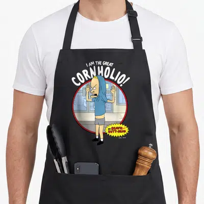 Butt beaverton apron - I AM THE GREAT CORNHOLIO text over character in red circle with yellow burst logo — shown on a black cotton canvas apron against a white background