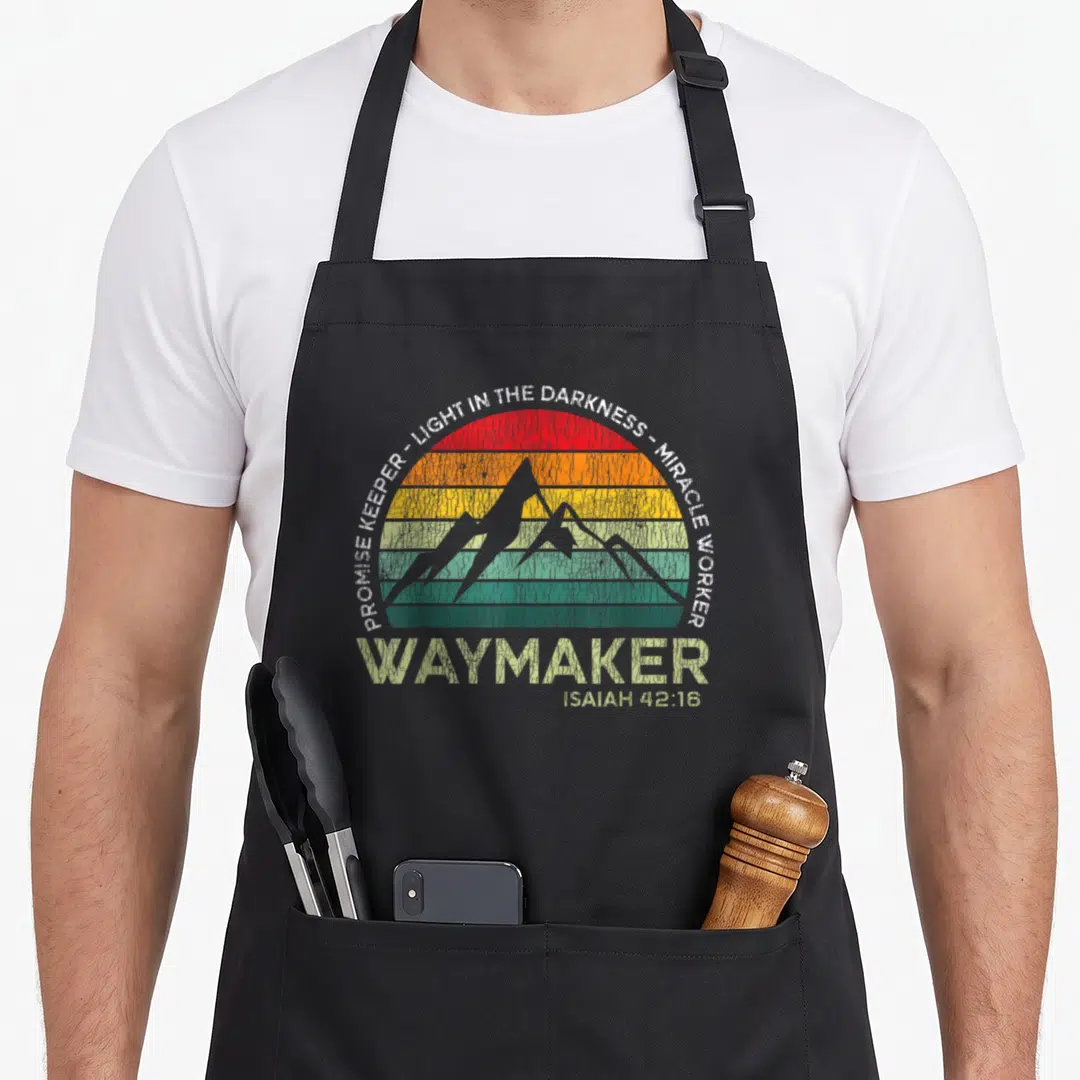 Waymaker christian apron - Retro sunset with mountains and Promise Keeper Waymaker Isaiah 42:16 text — shown on a black cotton canvas apron against a white background