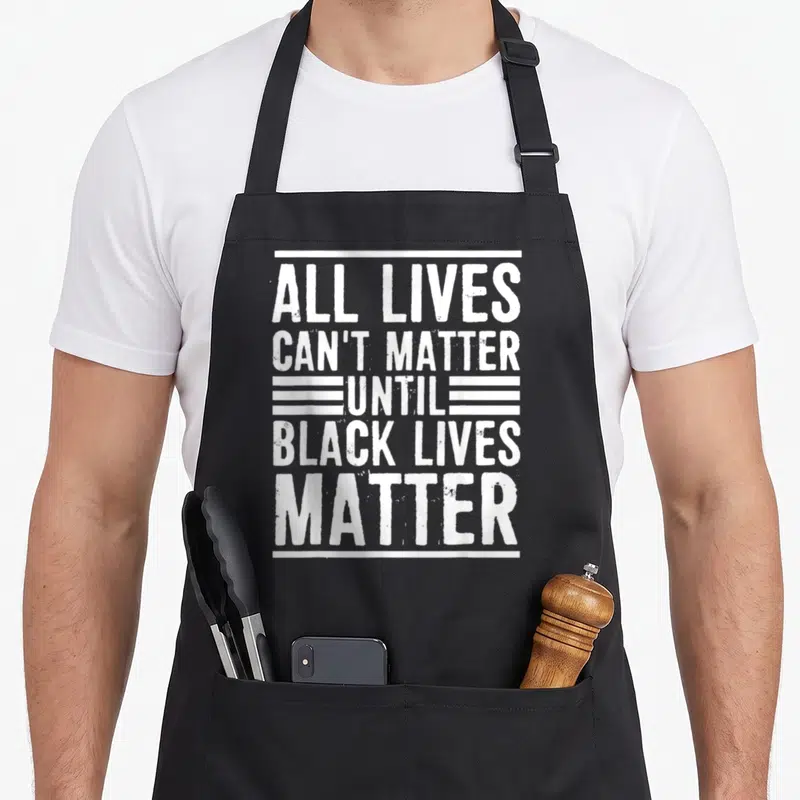 Live novelty apron - Stacked white distressed text reading All Lives Can't Matter Until Black Lives Matter framed — shown on a black cotton canvas apron against a white background