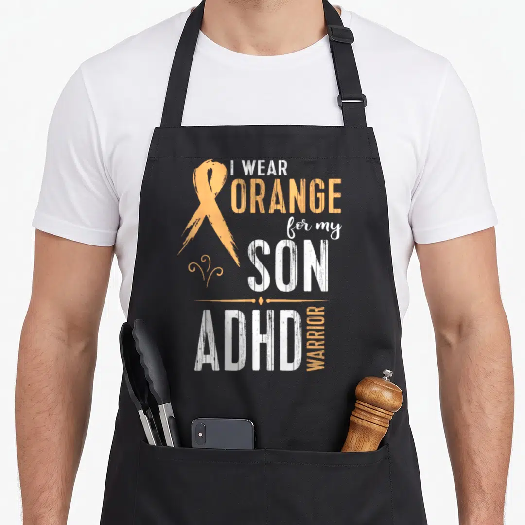 Walk adhd apron - Orange awareness ribbon beside stacked white and orange text reading I WEAR ORANGE for my SON ADHD — shown on a black cotton canvas apron against a white background