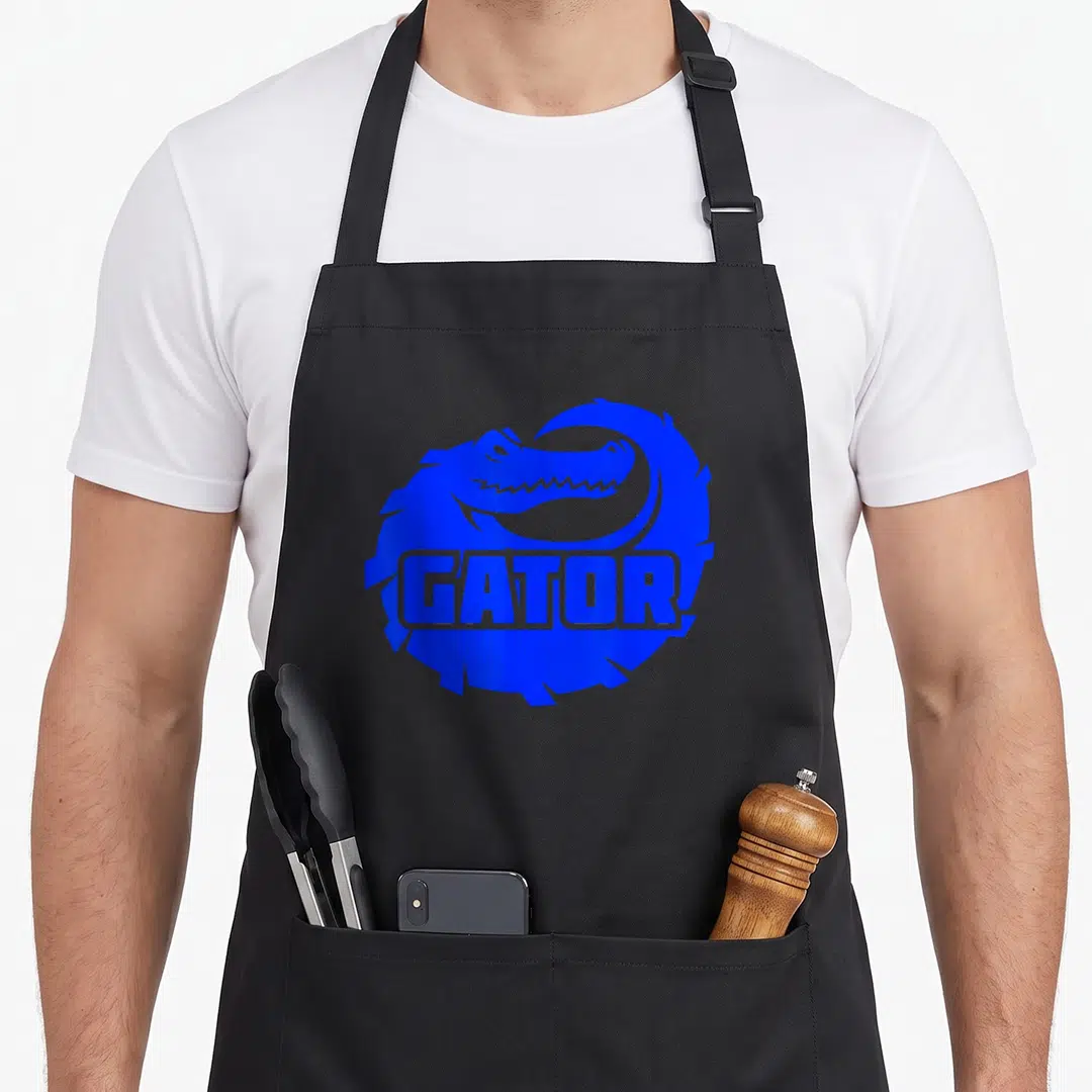 Funny gatorade apron - Blue alligator curled in circle with GATOR text across body — shown on a black cotton canvas apron against a white background
