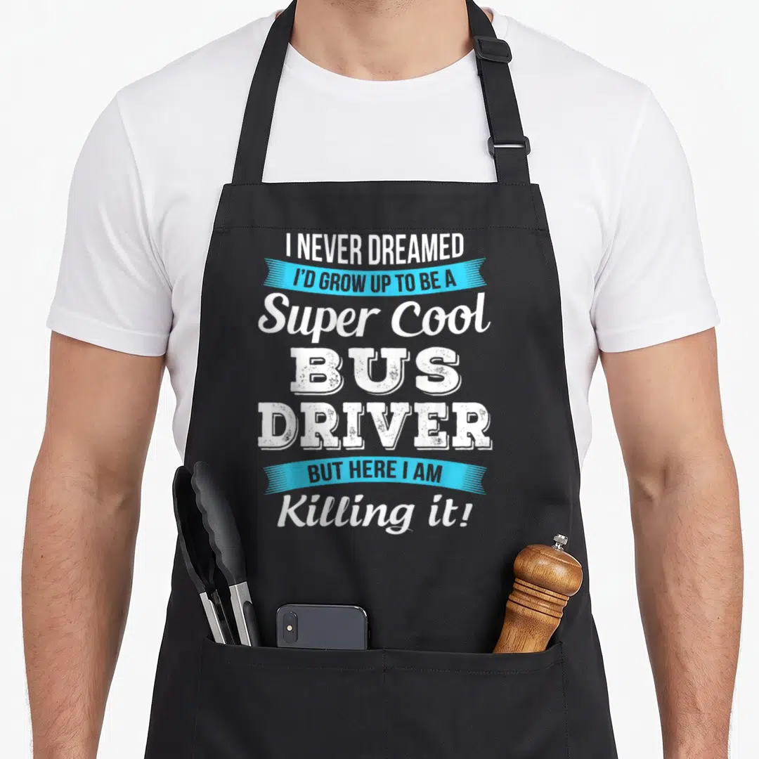 Funny bus driver apron - Stacked white text with light blue ribbons reading I NEVER DREAMED I'D GROW UP TO BE A Super — shown on a black cotton canvas apron against a white background