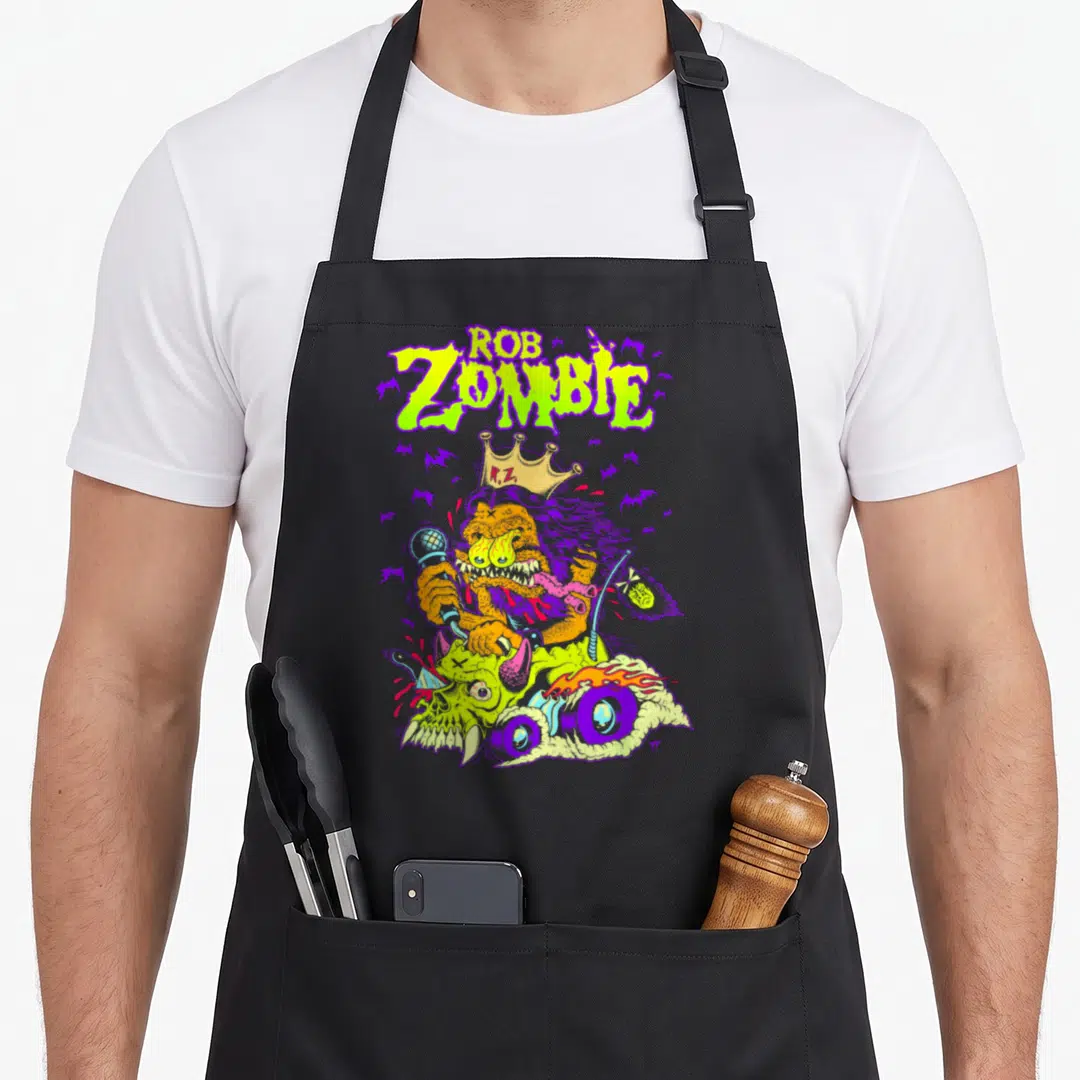 Rob king apron - Lime green ROB ZOMBIE text above an orange monster with a crown riding a purple motorcycle surrounded — shown on a black cotton canvas apron against a white background