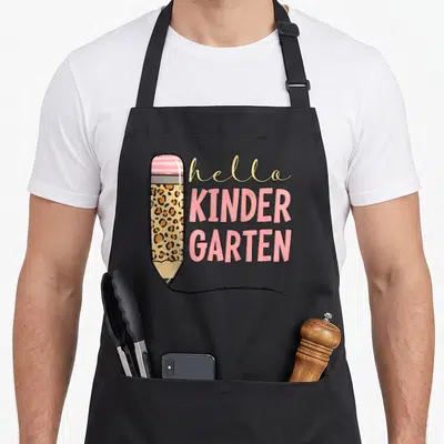 Pencil hello apron - Leopard print pencil with pink eraser and stacked hello KINDER GARTEN text in pink and tan — shown on a black cotton canvas apron against a white background