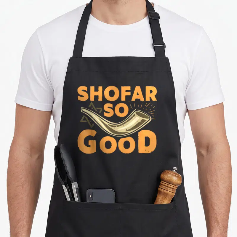 Shofar jewish apron - Cartoon shofar with SHOFAR SO GOOD text and star of david in orange beige brown — shown on a black cotton canvas apron against a white background