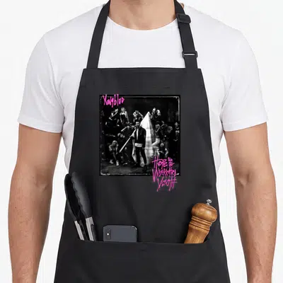Yungblud youth apron - Pink graffiti text YUNGBLUD and Hope for the Underrated Youth above black and white crowd photo — shown on a black cotton canvas apron against a white background