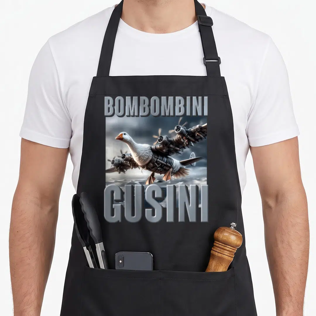 Bombombini italian apron - Goose with jet engines between BOMBOMBINI and GUSINI text in grey and white — shown on a black cotton canvas apron against a white background