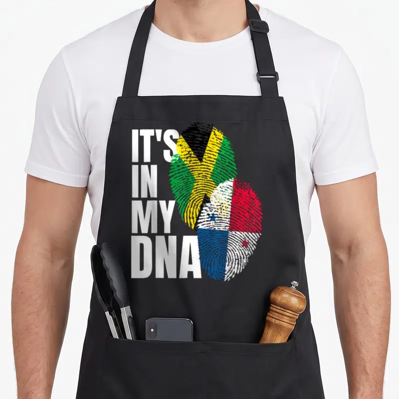 Panamanian heritage aprons - Stacked white text IT'S IN MY DNA beside two overlapping fingerprints filled — shown on a black cotton canvas apron against a white background