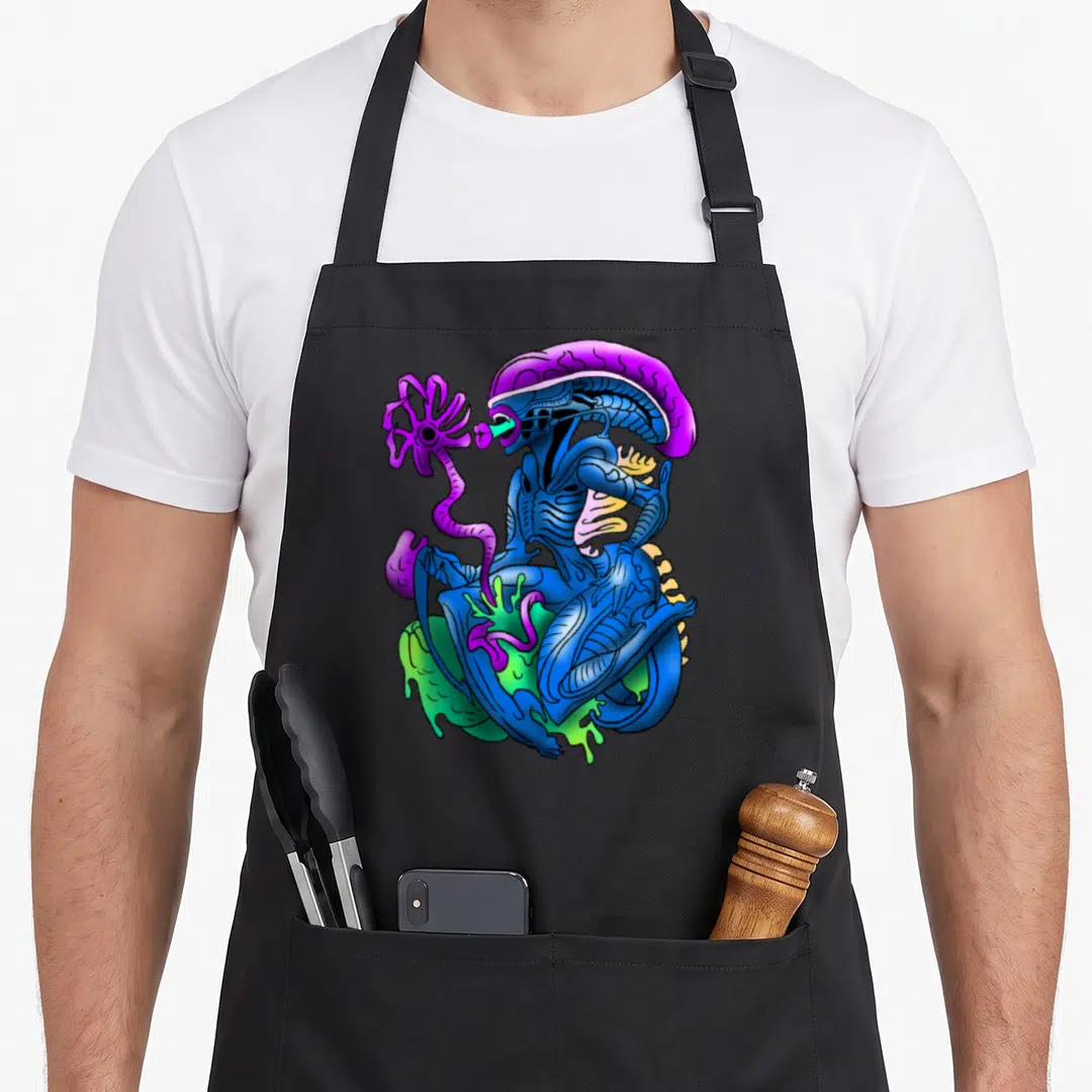 Alien cartoon apron - Blue xenomorph holding purple flower sitting in green slime cartoon style — shown on a black cotton canvas apron against a white background