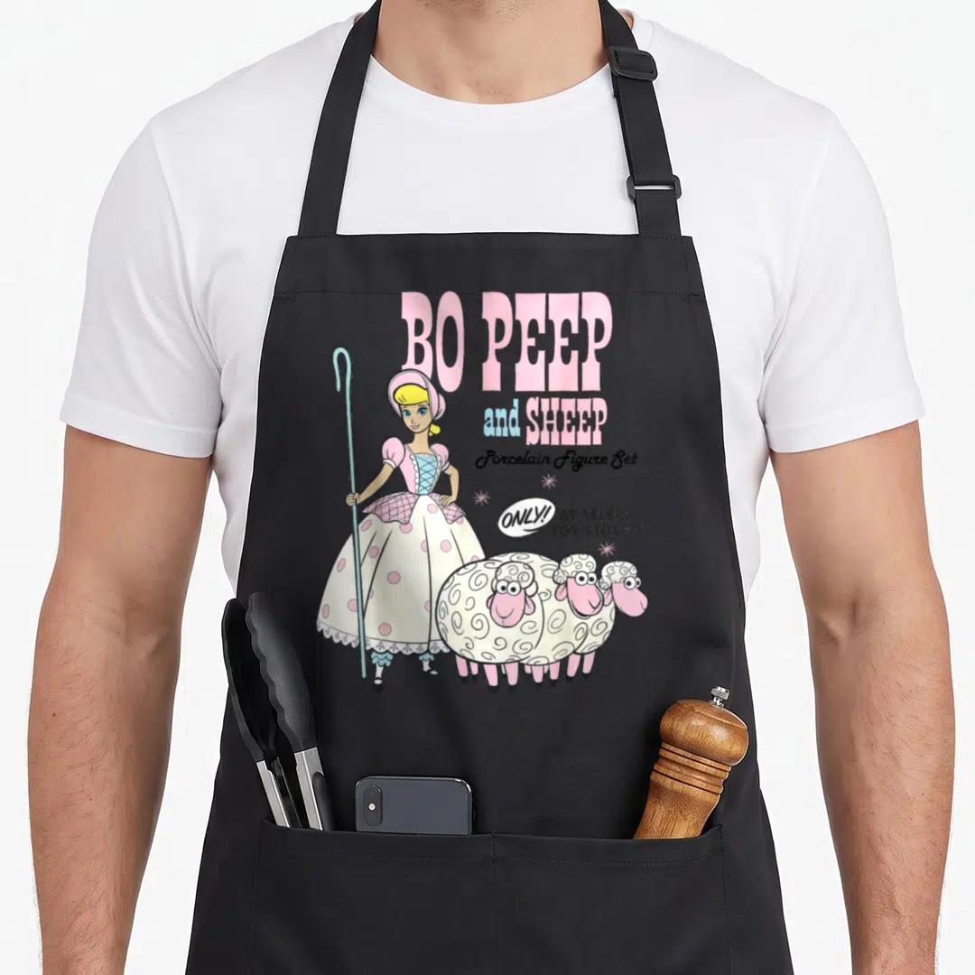 Peep sheep apron - Bo Peep holding crook with three sheep and vintage toy store ad text — shown on a black cotton canvas apron against a white background
