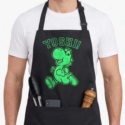 Funny run holiday apron - Green running cartoon dinosaur with arched YOSHI! text in black outline — shown on a black cotton canvas apron against a white background