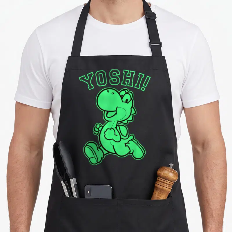 Funny run holiday apron - Green running cartoon dinosaur with arched YOSHI! text in black outline — shown on a black cotton canvas apron against a white background