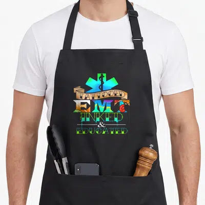 Tattooed paramedic apron - Star of Life with TATTOOED EMT INKED EDUCATED text filled with colorful art patterns — shown on a black cotton canvas apron against a white background