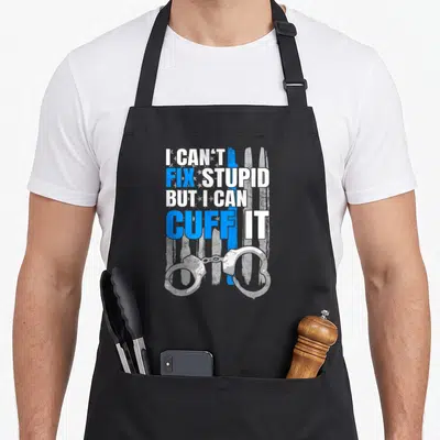 Handcuff police apron - I CAN'T FIX STUPID BUT I CAN CUFF IT text with handcuffs and distressed blue line flag — shown on a black cotton canvas apron against a white background