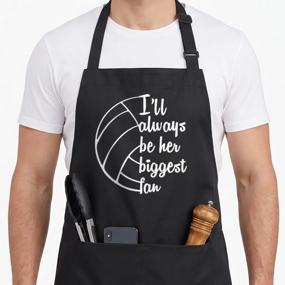 Coach volleyball dad apron - White line art volleyball with stacked text I'll always be her biggest fan — shown on a black cotton canvas apron against a white background