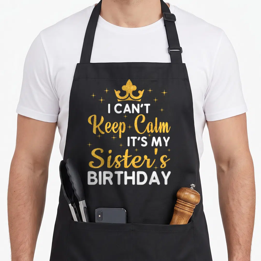 Funny sister birthday apron - Gold crown and white text I Can't Keep Calm It's My Sister's Birthday with stars — shown on a black cotton canvas apron against a white background