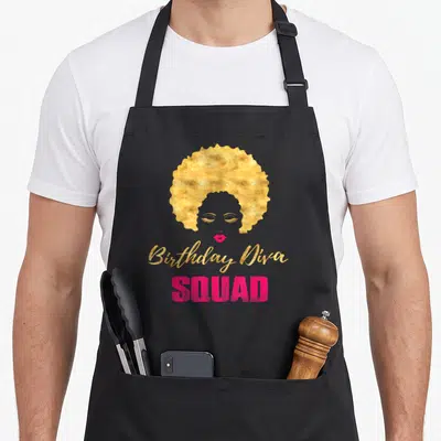 Diva squad birthday apron - Stylized woman face with gold afro and Birthday Diva SQUAD text in gold and pink — shown on a black cotton canvas apron against a white background