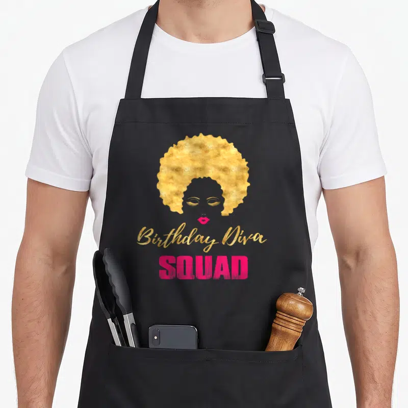 Diva squad birthday apron - Stylized woman face with gold afro and Birthday Diva SQUAD text in gold and pink — shown on a black cotton canvas apron against a white background
