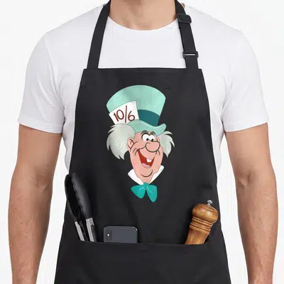 Face alice wonderland apron - Cartoon Mad Hatter head with teal hat, peach skin, and 10/6 price tag — shown on a black cotton canvas apron against a white background