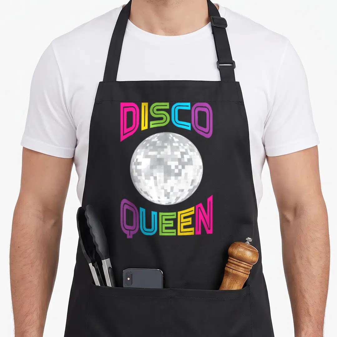 Disco queen seventy 70s apron - Silver disco ball surrounded by arched pink yellow green blue and purple text reading — shown on a black cotton canvas apron against a white background